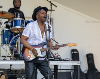 Photo of a lead singer in a band on stage and playing an electric guitar