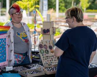 Photo from the 2023 Meridian Pride event with a jewelry vendor speaking to a customer.